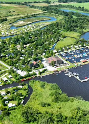 Luchtfoto van Vakantiepark Cnossen Leekstermeer, met het campingterrein, jachthaven en waterrijk natuurgebied De Onlanden