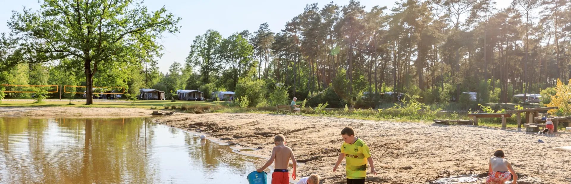 Kinderen spelen in het zand bij de speelvijver van Ardoer camping Diana Heide.