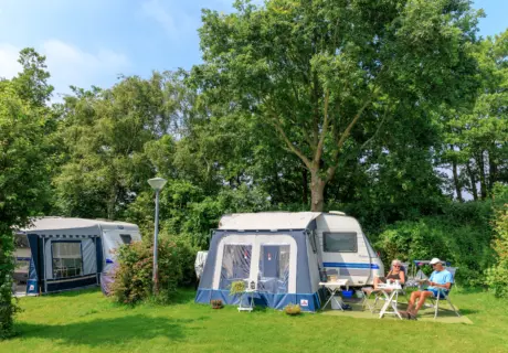 Ruime kampeerplaats met caravan en voortent op Camping Ginsterveld in Zeeland