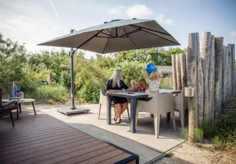Familie op het terras van chalet op Camping & Beachresort Julianahoeve in Zeeland