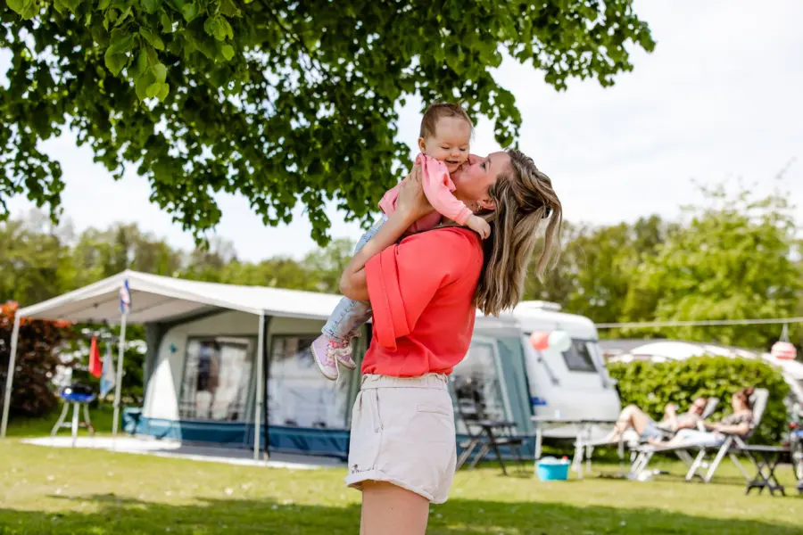 Kamperen moeder knuffelt met haar kindje