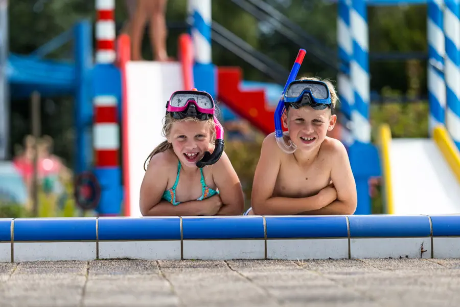 It Wiid twee kinderen poseren op zwembad rand