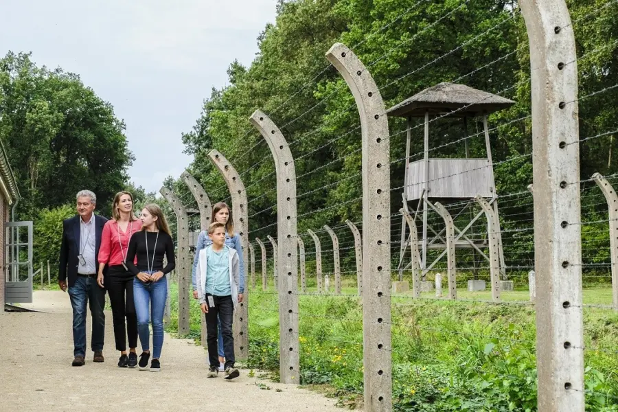Bezoekers op buitenterrein bij kampgracht en reconstructie wachttoren en barak foto jan van de ven
